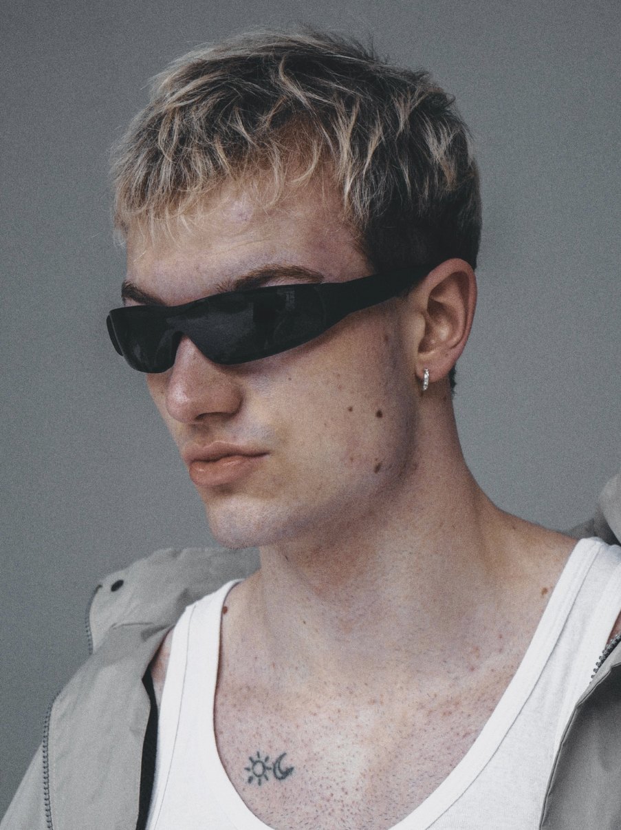Portret chłopaka w sportowych okularach przeciwsłonecznych, szare tło